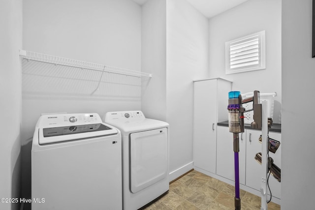 laundry room with stone finish floor, baseboards, laundry area, and washing machine and dryer