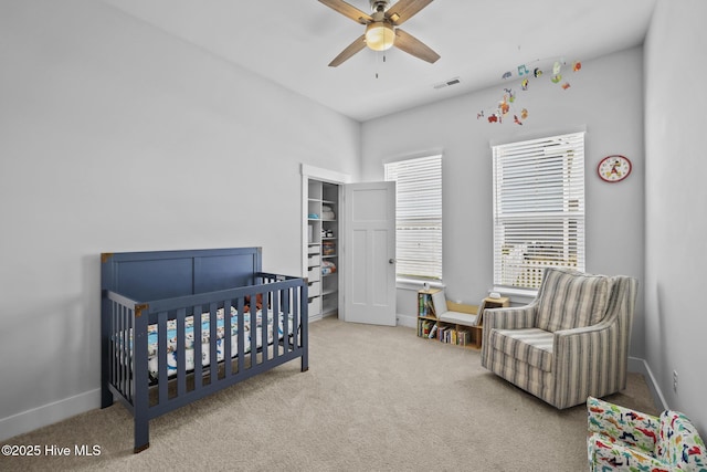 bedroom featuring a crib, baseboards, and carpet