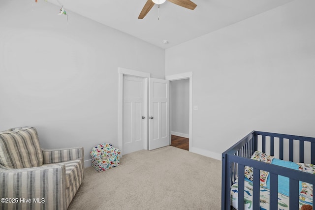 bedroom featuring baseboards, ceiling fan, carpet, and a crib