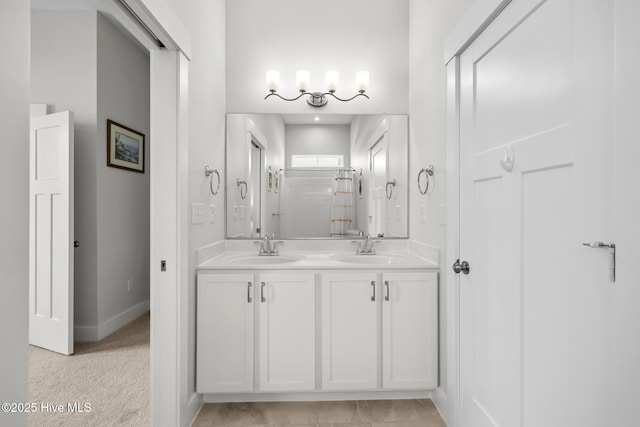 bathroom with a sink, baseboards, a stall shower, and double vanity