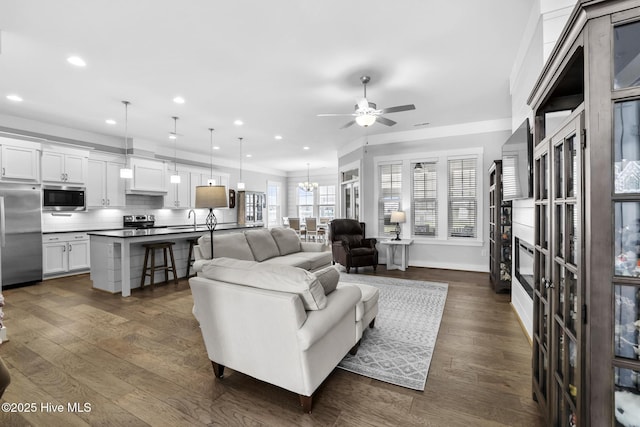 living room with recessed lighting, baseboards, dark wood finished floors, and ceiling fan with notable chandelier