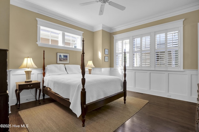 bedroom with wainscoting, multiple windows, and a decorative wall