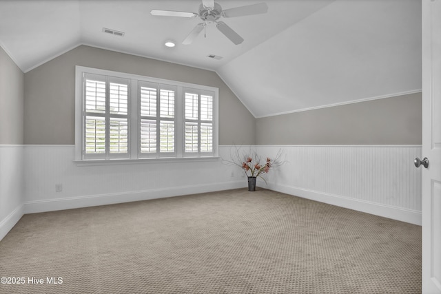additional living space with visible vents, wainscoting, and vaulted ceiling
