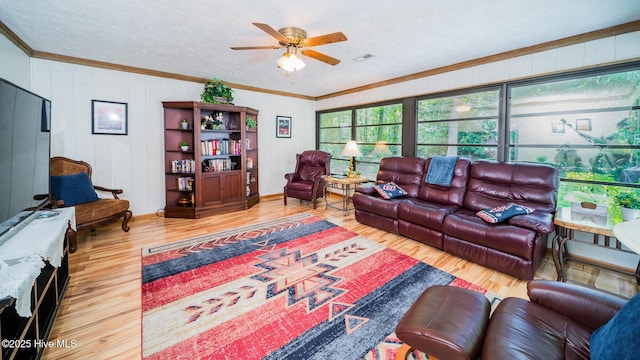 living area with crown molding, a ceiling fan, baseboards, wood finished floors, and visible vents