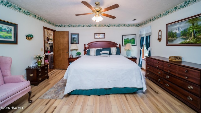 bedroom with light wood-style floors, a ceiling fan, a textured ceiling, and visible vents