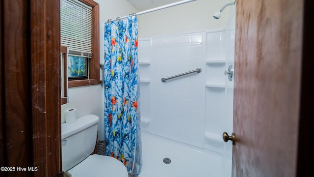 bathroom featuring toilet and curtained shower