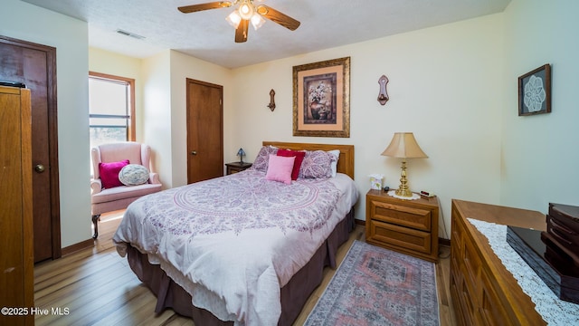 bedroom with visible vents, baseboards, light wood-type flooring, a textured ceiling, and a ceiling fan