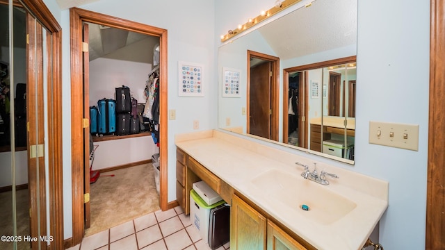 bathroom with vanity, baseboards, and tile patterned floors