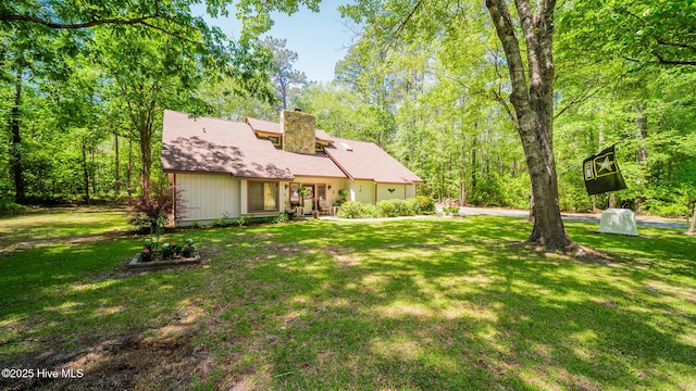 back of house featuring a lawn and a chimney
