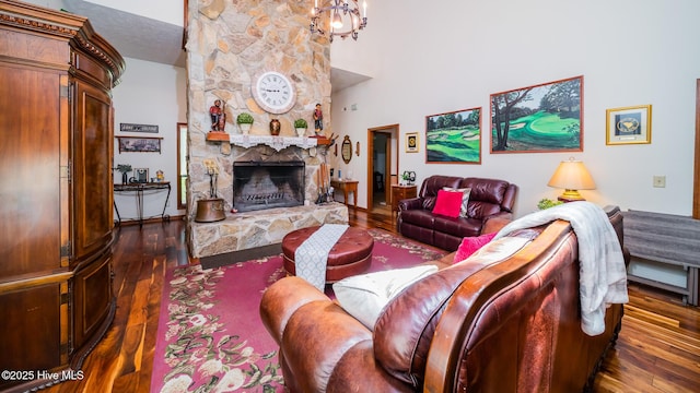 living room with a stone fireplace, a towering ceiling, and dark wood-style floors