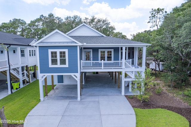 229 NE 34th St, Oak Island, NC 28465 - coastal home featuring a carport, driveway, a front yard, a shingled roof, and a standing seam roof