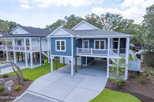229 NE 34th St, Oak Island, NC 28465 - beach home featuring a carport, covered porch, roof with shingles, concrete driveway, and stairway