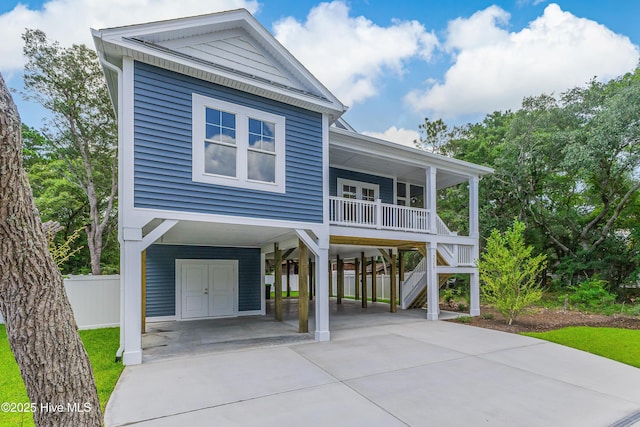 229 NE 34th St, Oak Island, NC 28465 - raised beach house featuring a carport, stairs, covered porch, and concrete driveway