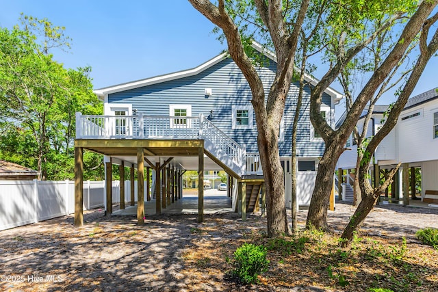 exterior space featuring a wooden deck, fence, stairway, and a carport