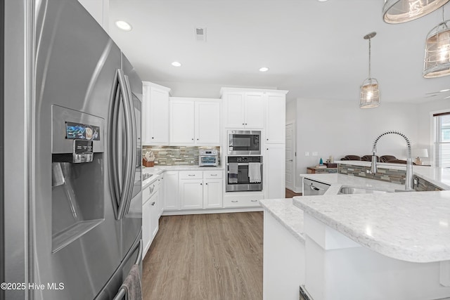 305 Ivy Ln, Carolina Beach, NC 28428 - kitchen with appliances with stainless steel finishes, a sink, backsplash, light wood-type flooring, and hanging light fixtures