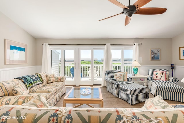 living area with french doors, a wealth of natural light, wood finished floors, and a wainscoted wall