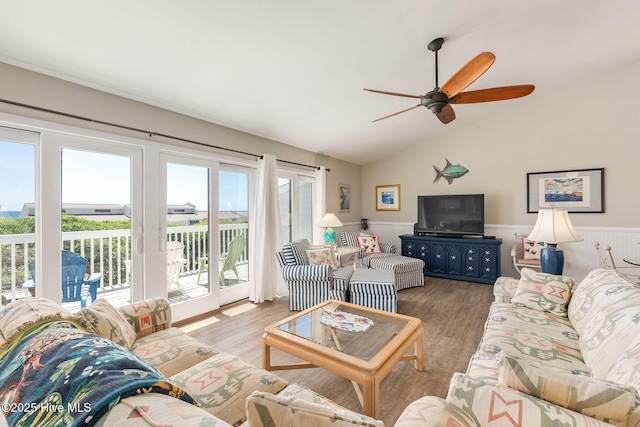 living room featuring wainscoting, ceiling fan, wood finished floors, and vaulted ceiling