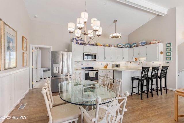 dining area featuring visible vents, high vaulted ceiling, beamed ceiling, a notable chandelier, and light wood-style flooring