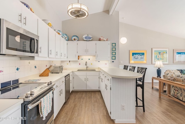 kitchen with a sink, light wood-style flooring, appliances with stainless steel finishes, and a breakfast bar area