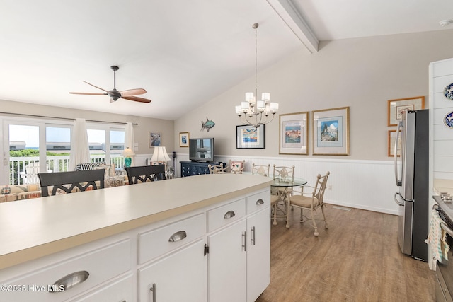 kitchen featuring wainscoting, light wood-style floors, light countertops, freestanding refrigerator, and vaulted ceiling with beams