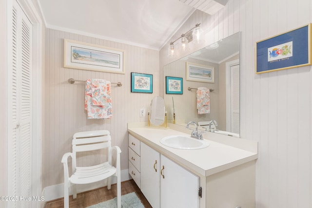 bathroom with a closet, ornamental molding, vanity, lofted ceiling, and wood finished floors