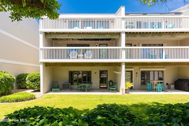 rear view of house with a lawn, a patio, stucco siding, and cooling unit
