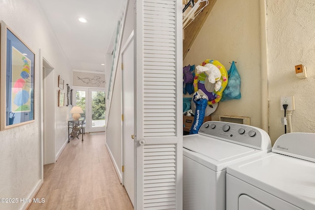laundry room featuring laundry area, a textured wall, washer and dryer, light wood-style floors, and baseboards