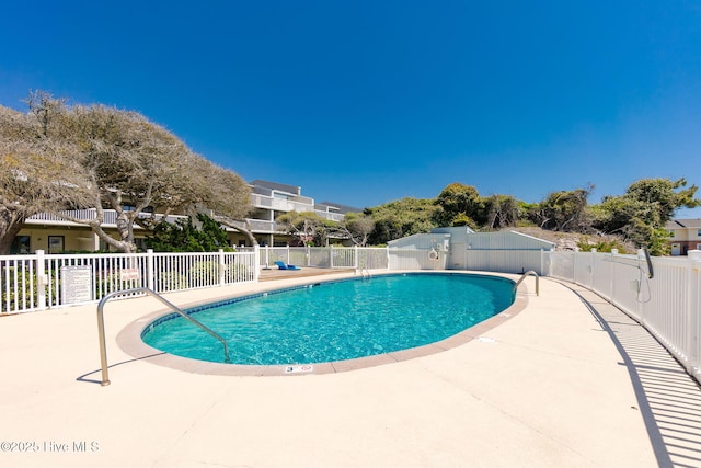 pool with a patio area and fence