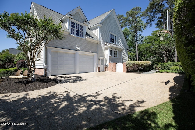 view of side of property with an attached garage, roof with shingles, driveway, and brick siding