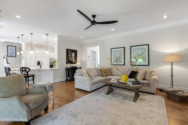 living area featuring ornamental molding, wood finished floors, baseboards, recessed lighting, and a ceiling fan