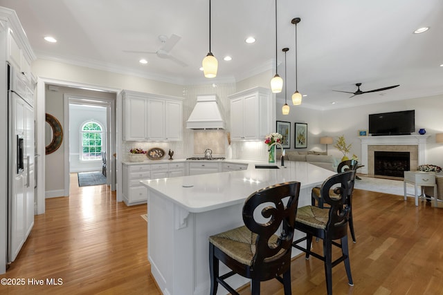 kitchen featuring ceiling fan, light countertops, a fireplace with raised hearth, a peninsula, and white cabinetry
