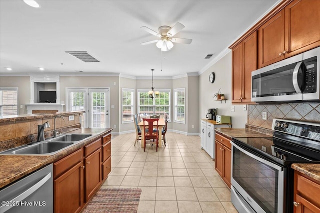kitchen with brown cabinetry, a sink, decorative backsplash, and stainless steel appliances