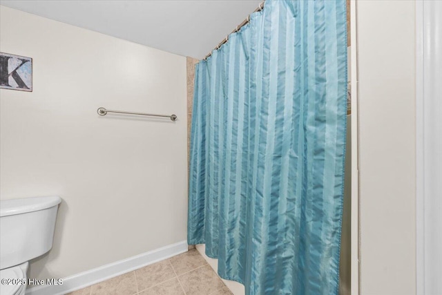 bathroom featuring baseboards, a shower with shower curtain, tile patterned floors, and toilet