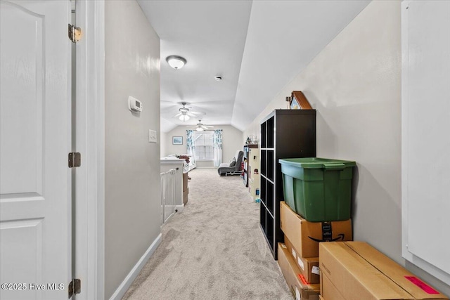corridor featuring carpet floors, baseboards, and vaulted ceiling