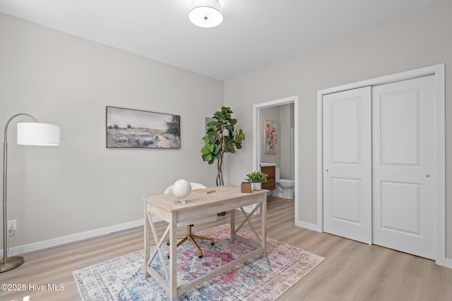 home office featuring baseboards and light wood finished floors