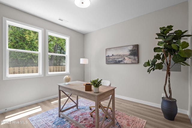 home office featuring baseboards, light wood-type flooring, and visible vents