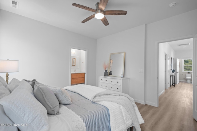 bedroom with baseboards, visible vents, ensuite bathroom, and light wood-style floors
