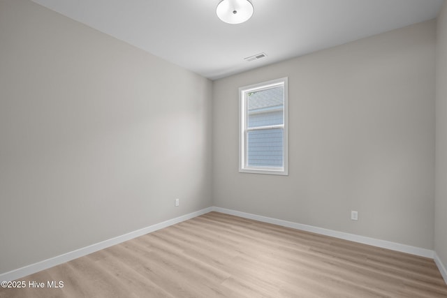 empty room featuring baseboards, light wood-type flooring, and visible vents