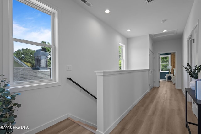 corridor featuring attic access, baseboards, an upstairs landing, light wood-type flooring, and visible vents