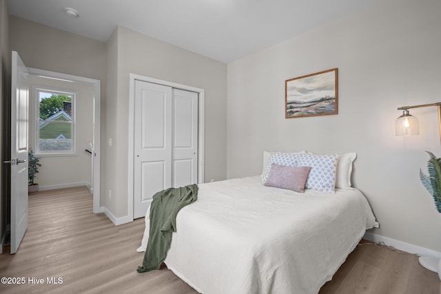 bedroom with light wood-type flooring, baseboards, and a closet