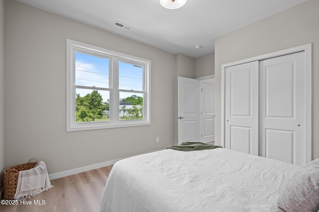 bedroom with visible vents, light wood-style flooring, baseboards, and a closet