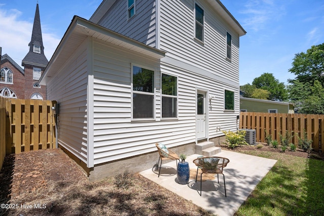 rear view of house with entry steps, fence, a patio, and central air condition unit