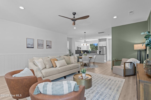 living room with light wood-style floors, ceiling fan with notable chandelier, recessed lighting, and visible vents