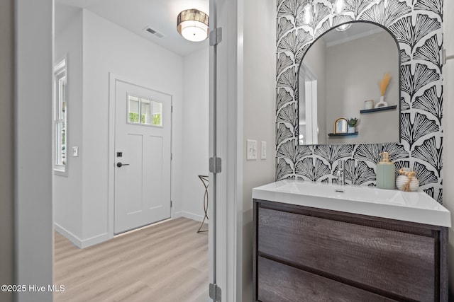 bathroom featuring vanity, baseboards, wood finished floors, tasteful backsplash, and visible vents