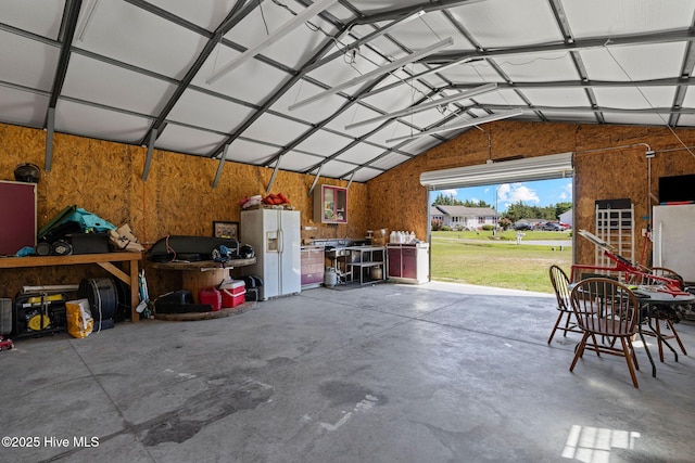 garage with white refrigerator with ice dispenser and freestanding refrigerator
