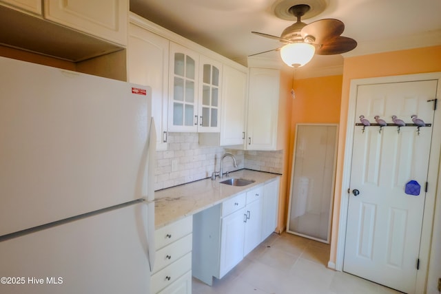 121 NW 1st St, Oak Island, NC 28465 - kitchen with freestanding refrigerator, decorative backsplash, glass insert cabinets, white cabinetry, and a sink