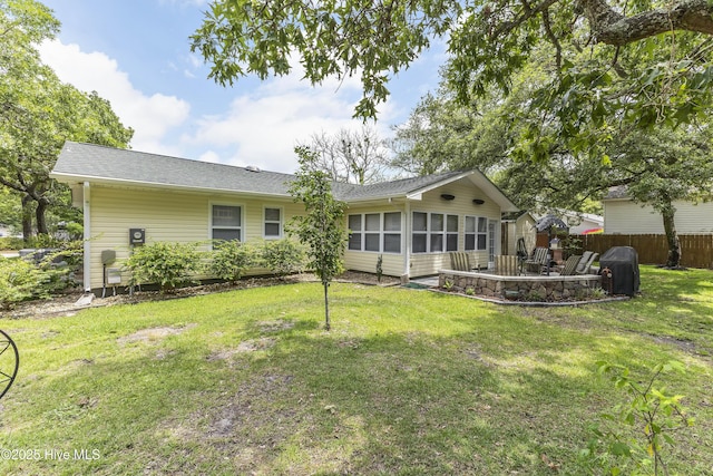 121 NW 1st St, Oak Island, NC 28465 - rear view of property with roof with shingles, a lawn, a sunroom, fence, and a patio
