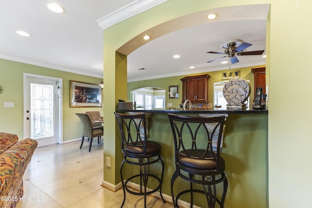 121 NW 1st St, Oak Island, NC 28465 - interior space with a ceiling fan, a kitchen bar, dark countertops, arched walkways, and ornamental molding