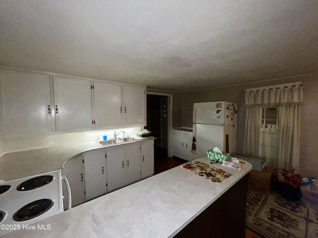 kitchen with a sink, light countertops, white cabinets, a peninsula, and white appliances