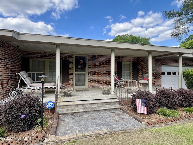 property entrance with brick siding, a garage, and covered porch